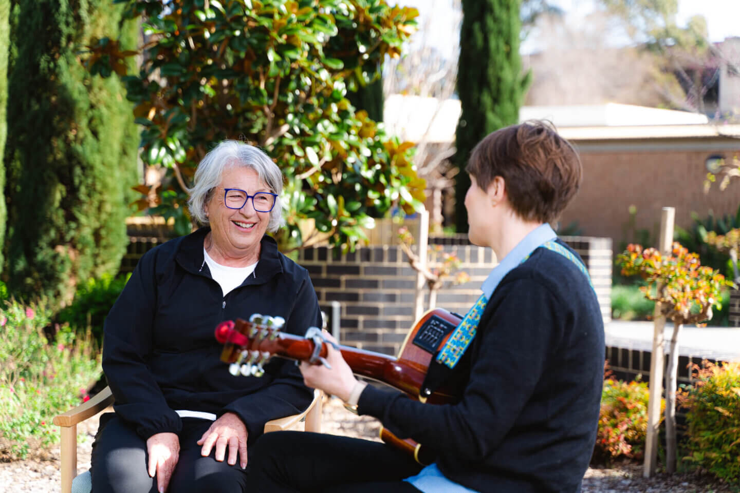 ECH resident learning guitar in Music Therapy class with ECH employee